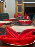 a table with red napkins and a plate with a red bow at Hotel Alpine Musk in Kanatal