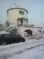 a black car parked in the snow in front of a lighthouse at De Witte Molen Kranenburg in Kranenburg