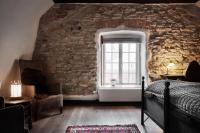 1 dormitorio con pared de piedra, cama y ventana en Hotel Helgeand Wisby, en Visby