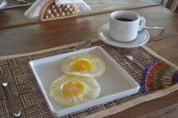 阿廷斯Pousada Vila Camurim的盘子里放着两个煎蛋，旁边是一杯咖啡。
