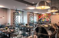 um restaurante com mesas e cadeiras e um quadro na parede em Amarant Urban Hotel by CHM em Kiev