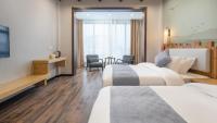 池州市にあるFloral Hotel Banxia Jiuhuashan Transfer Centerのベッド2台とテーブルがあるホテルの部屋