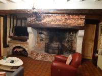 a living room with a brick fireplace and a red chair at les orchidees sauvages in Touffreville-la-Corbeline