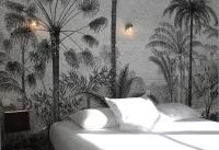 a bedroom with a bed with palm trees on the wall at Hotel Les Palmiers in Sainte-Maxime
