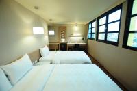 a hotel room with two beds and a desk at Kindness Hotel - Kaohsiung Main Station in Kaohsiung