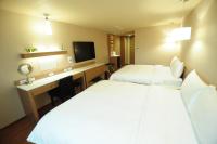 a hotel room with two beds and a desk at Kindness Hotel - Kaohsiung Main Station in Kaohsiung