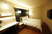 a hotel room with a bed and a desk and a computer at Kindness Hotel - Kaohsiung Main Station in Kaohsiung