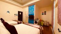 a bedroom with two beds and a tv in it at Hai Yang Feng Qing Homestay in Hualien City