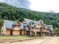 a large wooden house with a blue roof at Apartman Pustolov - Stara planina in Crni Vrh