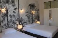 two beds in a room with palm trees wallpaper at Hotel Les Palmiers in Sainte-Maxime