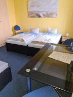 a room with two beds and a table with a laptop at Hanse Haus Pension in Greifswald