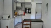 a kitchen with white cabinets and a table and a microwave at LA PARENTHÈSE AU PAYS DU VERT in Soucht
