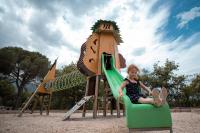 a young girl sitting on a slide at a playground at Camping Les Albères - Maeva in Laroque-des-Albères