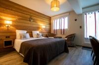 a bedroom with a bed with wooden walls and windows at Logis Le Vernay in Autrans