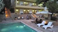 a house with a swimming pool with chairs and an umbrella at PLEIADES lUXURY APARTMENTS in Porto Heli