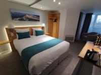 Un dormitorio con una cama grande en una habitación de hotel. en Contact Hôtel Le Provençal Bordeaux Lac, en Burdeos