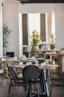 Un comedor con mesas y sillas de madera. en The Capital Zimbali, en Ballito