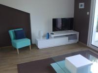 a living room with a tv and a blue chair at Apartment Les Berges Landaises-1 by Interhome in Soorts-Hossegor