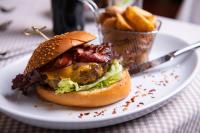 グミュント・イン・ケルンテンにあるHotel Restaurant Platzerのフライドポテトの入ったバスケットと皿に載ったチキンサンドイッチ