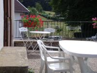 a white table and chairs on a patio with flowers at Gîte Les Hirondelles in Plombières-les-Bains