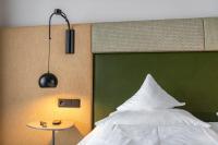 a bedroom with a bed with a green headboard and a table at Hotel Jakob in Fuschl am See