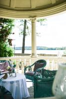 Un porche con sillas y mesas y vista al agua. en Hotel Solar Palace SPA & Wellness, en Mrągowo