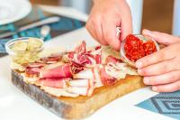 una persona está preparando un sándwich en una tabla de cortar en Albergo Residenziale Menhirs, en Putzu Idu