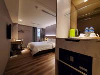 a hotel room with a bed and a kitchen with water bottles at HINOEN Hotel in Taipei