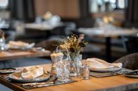 uma mesa com pratos e copos e um vaso de flores em Ski & Bike Hotel Wiesenegg em Saalbach Hinterglemm