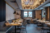 um restaurante com mesas longas, cadeiras e lustres em Ski & Bike Hotel Wiesenegg em Saalbach Hinterglemm