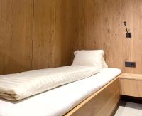 a bed with white sheets and a wooden wall at Apartmenthaus Anna in Lustenau