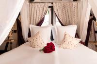 a white bed with two pillows and a red rose on it at Hotel Restaurant Le Maréchal - Teritoria in Colmar