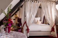 a bedroom with a canopy bed with a table and flowers at Hotel Restaurant Le Maréchal - Teritoria in Colmar