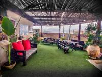 eine Terrasse mit Bänken, Tischen und Pflanzen in einem Gebäude in der Unterkunft הבית הלבן של נתן in Eilat