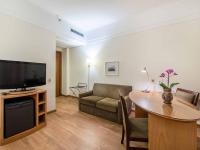 a living room with a table and a couch and a television at Hotel Cassino Tower Campinas Cambuí By Nacional Inn in Campinas