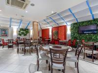 a restaurant with tables and chairs and a tv at Hotel Cassino Tower Campinas Cambuí By Nacional Inn in Campinas
