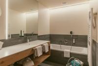 ein Badezimmer mit einer Badewanne und einem großen Spiegel in der Unterkunft TRAUBE BRAZ Alpen Spa Golf Hotel in Bludenz