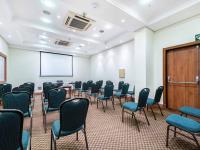 a conference room with chairs and a podium and a screen at Hotel Cassino Tower Campinas Cambuí By Nacional Inn in Campinas