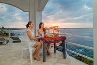 CuatunalcoにあるHotel Luz de Mar ' right on the beachの海の見えるバルコニーのテーブルに座った女性2名