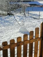 a snowman sitting in the snow behind a fence at Lucija in Lovinac