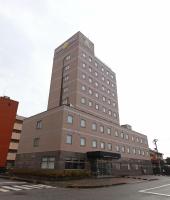 un edificio alto marrón sentado al lado de una calle en Smile Hotel Takaoka Ekimae, en Takaoka