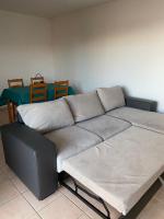 ein Sofa in einem Zimmer mit Tisch und Stühlen in der Unterkunft Appartement moderne en résidence avec piscine in Mèze