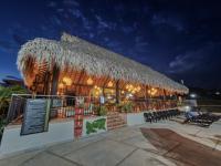 un restaurante con techo de paja, mesas y sillas en Hotel Arbóreo Doradal, en Doradal