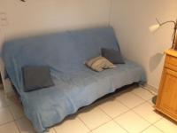 a blue couch with two pillows on it in a room at CAP D&#39;AGDE studio cabine 6 pers. + terrasse + parking privé + clim (calme) in Cap d&#39;Agde
