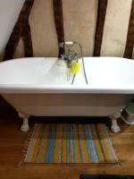 a white bath tub sitting on top of a rug at La Dragonne, petite maison au centre de Bellême, jardin, cuisine équipée, vue forêt in Bellême