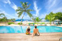 un hombre y una mujer sentados en un paseo de madera junto a una piscina en Pineapple Beach Villas, en Baie Lazare Mahé