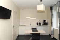 a white kitchen with a table and a tv on the wall at Aux Jardins de L&#39;Isle in Vienne