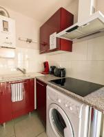 a kitchen with red cabinets and a washing machine at Appartement cosy avec parking proche port et plage in Cap d&#39;Agde