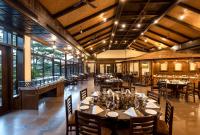 een eetkamer met tafels en stoelen en ramen bij Aahana Resort - Jim Corbett in Rāmnagar