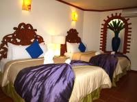 a hotel room with two beds with purple sheets at Ecotel Quinta Regia in Valladolid